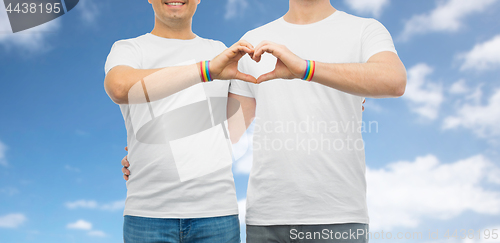 Image of couple with gay pride rainbow wristbands and heart