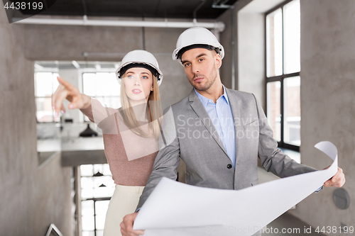 Image of architects with blueprint and helmets at office