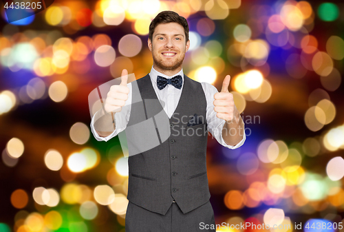 Image of happy man in suit showing thumbs up over lights 