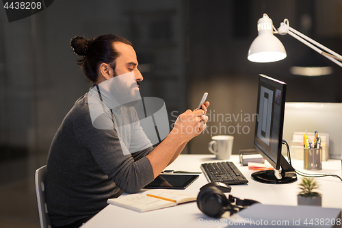 Image of creative man with smartphone at night office