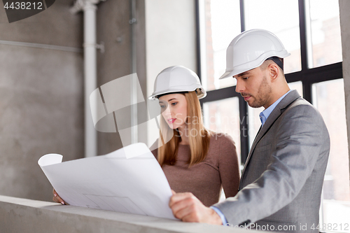 Image of architects with blueprint and helmets at office