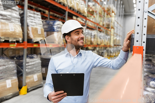 Image of businessman in helmet with clipboard at warehouse