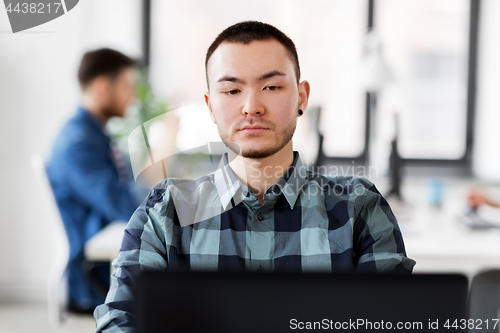 Image of creative man with laptop working at office