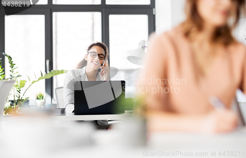 Image of businesswoman calling on smartphone at office