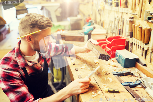 Image of carpenter working with wood plank at workshop