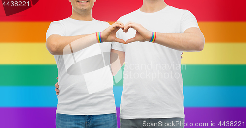 Image of couple with gay pride rainbow wristbands and heart