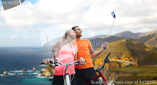 Image of couple with bicycle and smartphone selfie stick