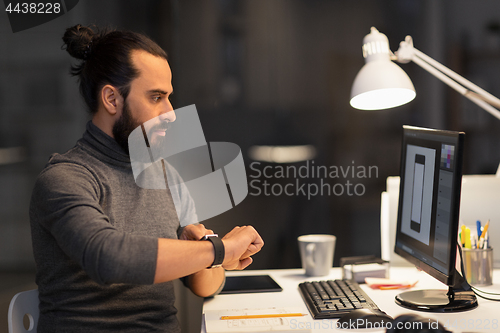 Image of designer with smartwatch and computer at office