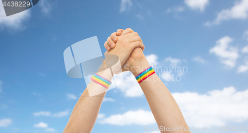 Image of hands with gay pride wristbands in winning gesture