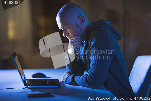 Image of hacker with laptop computer in dark room