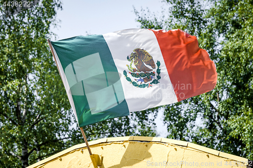 Image of Mexican flag on a yellow building waving