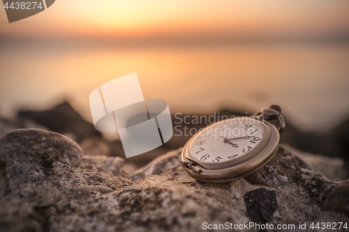 Image of Antique watch on a rock in the sunrise