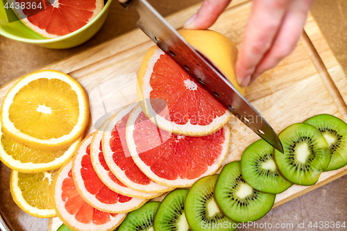 Image of Women\'s hands Housewives cut with a knife fresh grapefruit on th