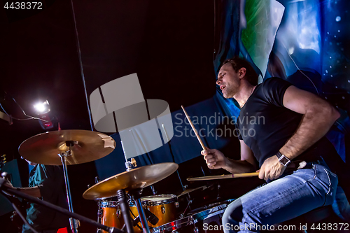 Image of Drummer playing on drum set on stage.