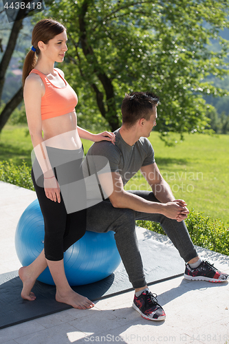 Image of woman and personal trainer doing exercise with pilates ball