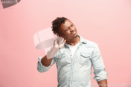 Image of The Ear ache. The sad Faro-American man with headache or pain on a pink studio background.