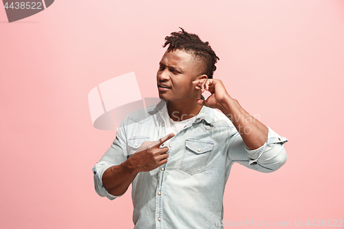 Image of The Ear ache. The sad Faro-American man with headache or pain on a pink studio background.