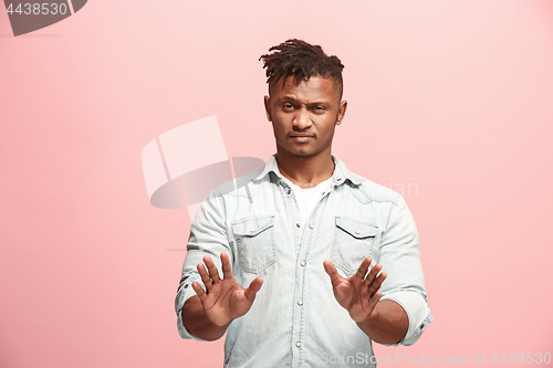 Image of Young man with disgusted expression repulsing something, isolated on the pink