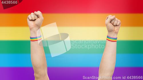 Image of hands with gay pride rainbow wristbands shows fist