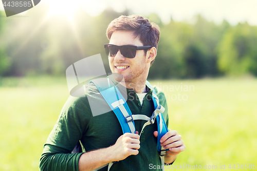 Image of happy young man with backpack hiking outdoors