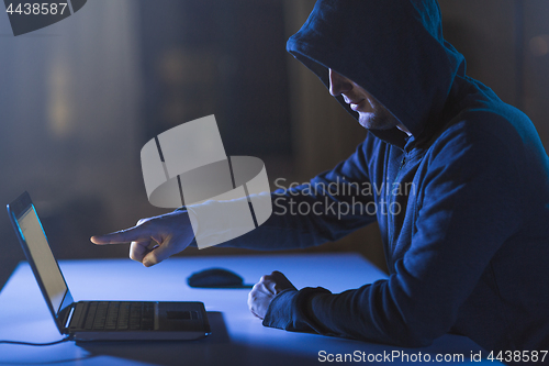 Image of hacker pointing at laptop computer in dark room