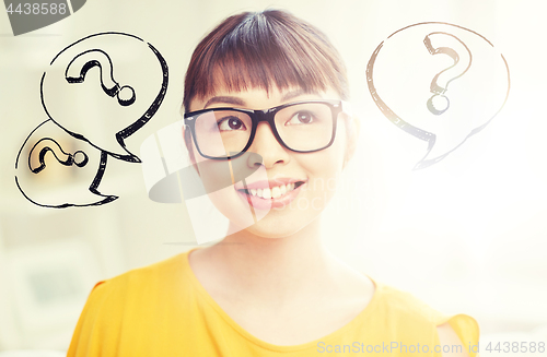 Image of happy asian woman in glasses over question marks