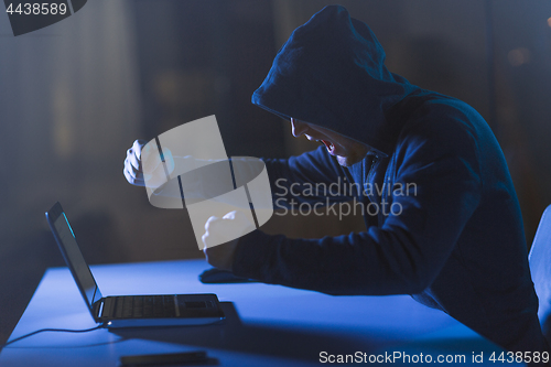 Image of angry hacker with laptop shouting in dark room