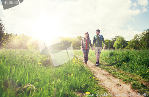 Image of happy couple with backpacks hiking outdoors