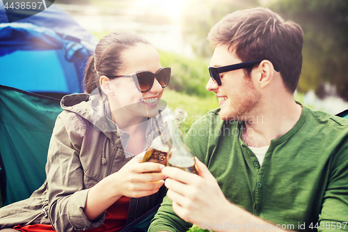 Image of happy couple clinking drinks at campsite tent