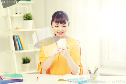 Image of happy young woman student with smartphone at home