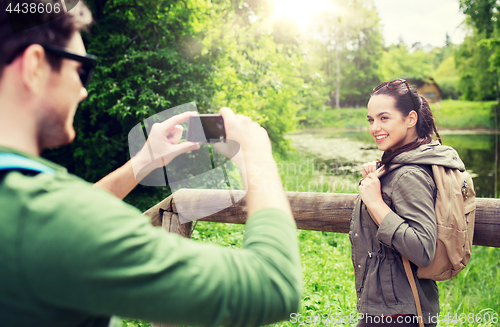 Image of couple with backpacks taking picture by smartphone