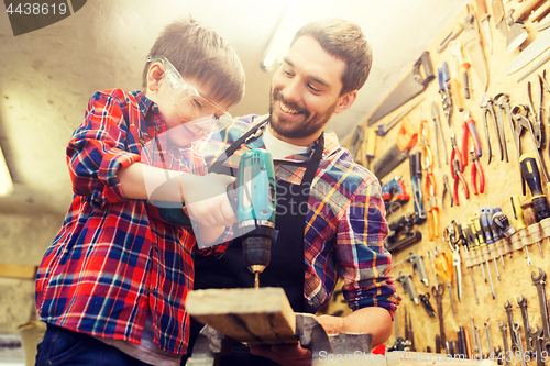 Image of father and son with drill working at workshop