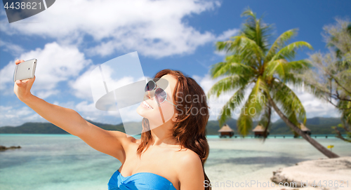 Image of woman taking selfie by smartphone on beach