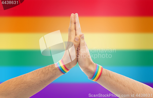 Image of hands with gay pride wristbands make high five