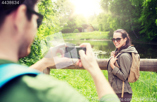 Image of couple with backpacks taking picture by smartphone