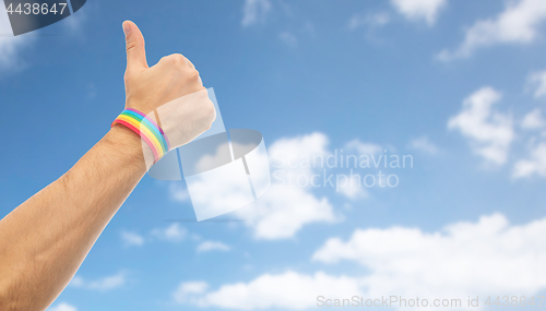 Image of hand with gay pride rainbow wristband shows thumb