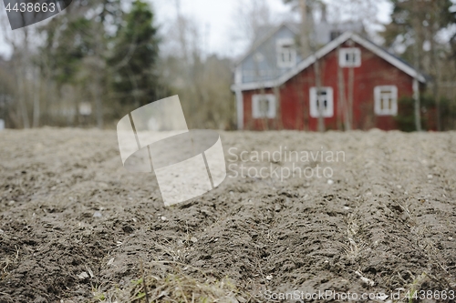 Image of farmhouse in blur behind a plowed field