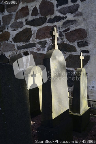 Image of tombstones with crosses in the cemetery near the church wall