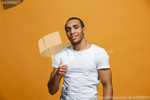 Image of The happy businessman standing and smiling against orange background.