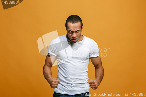 Image of The young emotional angry man screaming on orange studio background