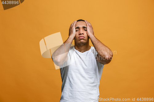 Image of Man having headache. Isolated over orange background.