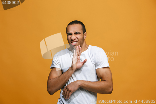 Image of The young man whispering a secret behind her hand over orange background