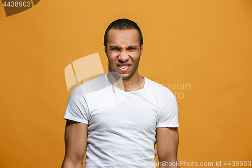 Image of Young man with disgusted expression repulsing something, isolated on the orange