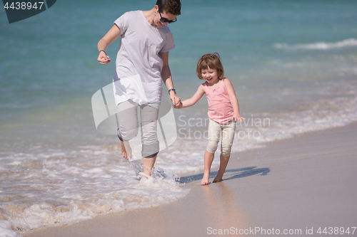 Image of mother and daughter running on the beach