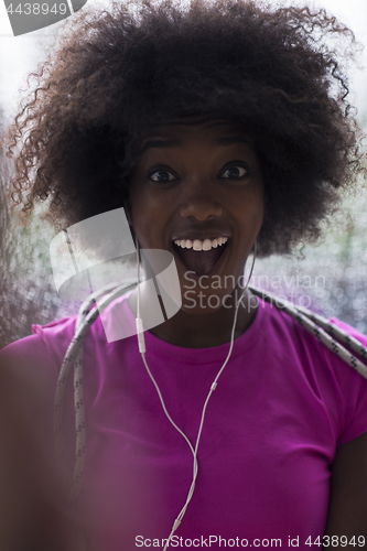 Image of portrait of young afro american woman in gym while listening mus