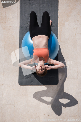Image of woman doing exercise with pilates ball top view