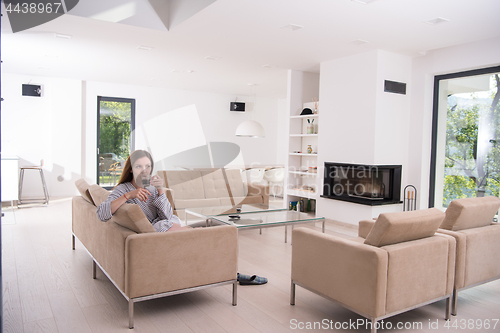 Image of young woman in a bathrobe enjoying morning coffee