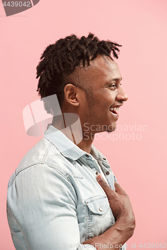 Image of The happy business Afro-American man standing and smiling against pink background. Profile view.