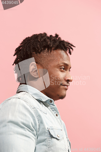 Image of The happy business Afro-American man standing and smiling against pink background. Profile view.