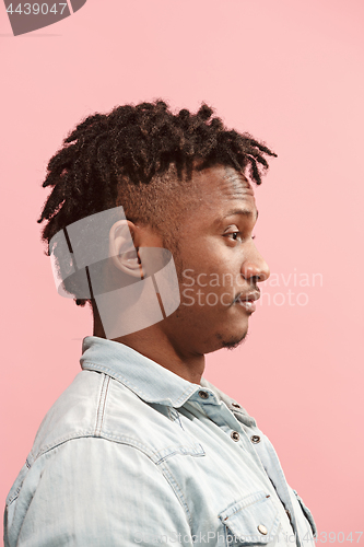 Image of The surprised business Afro-American man standing and looking pink background. Profile view.